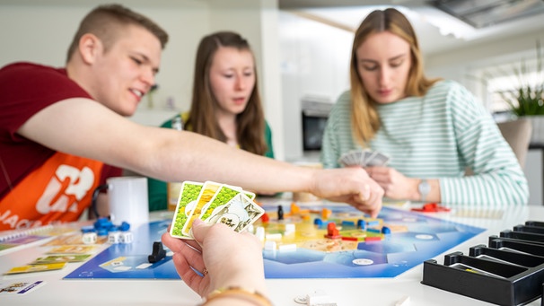 Spieleabend unter Freunden - Symbolbild. Wusstet ihr, dass Spiele wie "Mensch ärgere dich nicht", Mühle und Schach jahrhundertealt sind? Spielen lehrt uns, die Welt besser zu verstehen. | Bild: picture alliance / dpa-tmn | Benjamin Nolte