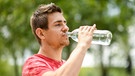 Ein junger Mann trinkt aus einer Wasserflasche. Trinken wir zu wenig leidet unser Körper. Wir erklären euch, wie viel Flüssigkeit ihr jeden Tag trinken solltet, damit ihr gesund und leistungsfähig bleibt und mit welchen Getränken stillt ihr euren Durst und Flüssigkeitsbedarf am besten stillt. | Bild: picture alliance/dpa Themendienst | Tobias Hase