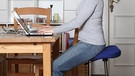 Richtig sitzen für einen gesunden Rücken: So wie im Bild (mit Stehhilfe) funktioniert' s ... Langes Sitzen kann schnell zu Rückenproblemen und Schmerzen führen. Doch es gibt einige Möglichkeiten, es dem Rücken angenehmer zu machen. | Bild: BR