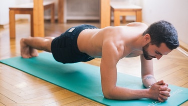 Ein Mann stützt sein Körpergewicht auf seinen Unterarmen ab. Schon zehn Minuten Rückentraining täglich machen einen großen Unterschied! Wir zeigen Ihnen die richtigen Übungen, damit Sie Ihren Rücken stärken und Rückenproblemen vorbeugen können. | Bild: BR/Johanna Schlüter