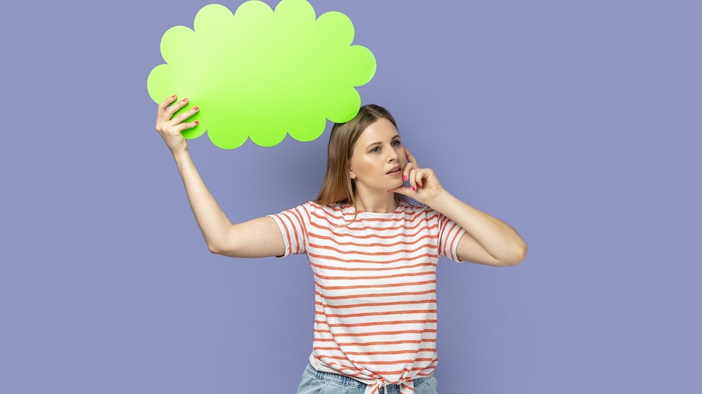 Frau mit grüner Pappe in Form einer Gedankenblase. Grübeln wir, bewegen sich unsere Gedanken wie in einem Gedankenkarussell. Wir erklären euch die Ursachen für euren Grübelzwang und wie ihr negative Gedanken stoppen könnt. | Bild: picture-alliance/dpa Frau mit grüner Pappe in Form einer Gedankenblase. Grübeln wir, bewegen sich unsere Gedanken wie in einem Gedankenkarussell. Wir erklären euch die Ursachen für euren Grübelzwang und wie ihr negative Gedanken stoppen könnt. | Bild: picture-alliance/dpa