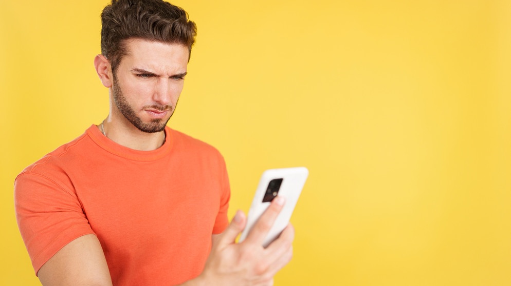 Mann schaut pessimistisch auf sein Handy. Die Prüfung geht sowieso schief, einen Job kriegt ihr nie, alle sind gegen euch. Denkt ihr oft so negativ? Wir erklären, warum manche Menschen eher Pessimisten oder Optimisten sind, was 'pessimistisch' bedeutet - und ob das wirklich immer schlecht ist. | Bild: colourbox.com