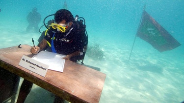 2009 verlegt der damalige maledivische Präsident Nasheed eine Kabinettssitzung unter Wasser. Die Malediven sind vom Klimawandel bedroht: Der flache Inselstaat droht buchstäblich "abzusaufen" - weil der Meerespiegel aufgrund der Eisschmelze immer weiter steigt. Der Klimawandel lässt das Eis der Polarregionen schmelzen. Dadurch steigt der Meeresspiegel immer schneller. Die Folgen für Menschen und Umwelt sind verheerend. | Bild: picture-alliance/dpa
