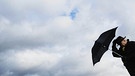 Mann kämpft mit Schirm gegen den Wind: Der Wind ist ein Wettertreiber. Der Wind beeinflusst er das Wetter, so viel ist klar. Er lässt die Sonne scheinen und treibt die Wolken an. Doch wie entstehen die Winde überhaupt? | Bild: picture-alliance/dpa
