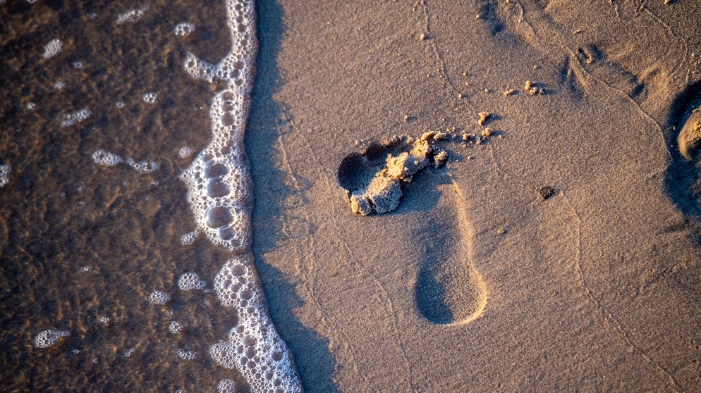 Unser Wasser-Fußabdruck ist ein Indikator, um unseren Wasserverbrauch auch bei Konsumgütern in den Blick zu bekommen; Fußabdruck im nassen Sand. | Bild: picture alliance/dpa/dpa-Zentralbild | Stefan Sauer Unser Wasser-Fußabdruck ist ein Indikator, um unseren Wasserverbrauch auch bei Konsumgütern in den Blick zu bekommen; Fußabdruck im nassen Sand. | Bild: picture alliance/dpa/dpa-Zentralbild | Stefan Sauer