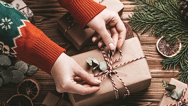 Eine Frau packt Geschenke ein. Weihnachtsbaum, Plätzchen, Braten und Geschenkpapier sind oft wenig umweltfreundlich. Wie ihr mit einfachen Tipps und Tricks ressourcenschonende und trotzdem schöne Weihnachten feiern könnt. | Bild: picture-alliance/dpa