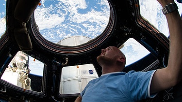 Der deutsche Astronaut Alexander Gerst schaut aus dem ISS-Ausguck ins Weltall und auf die Erde. | Bild: picture alliance/dpa